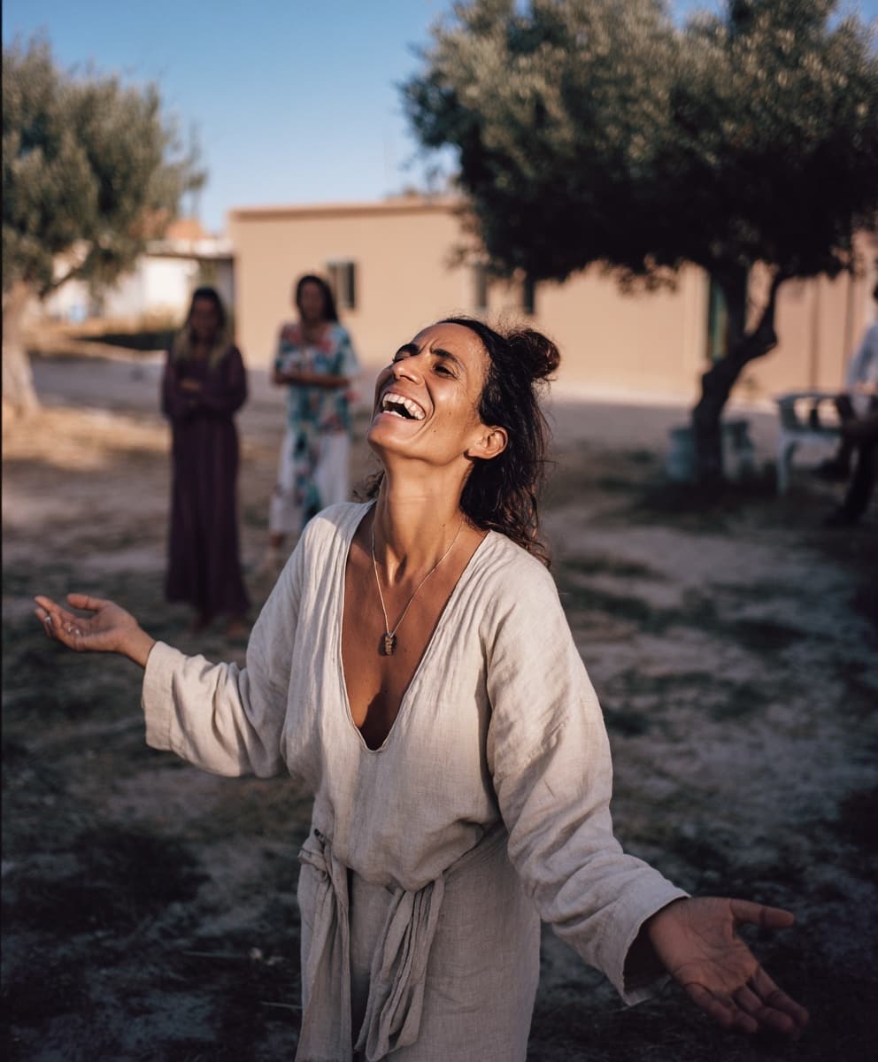 Mujer española feliz con los brazos abiertos en un pueblo de Senegal, simbolizando libertad y sanación emocional
